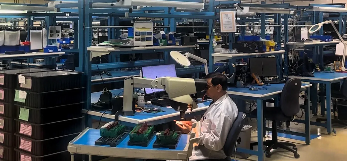 A technician inspecting circuit boards at an electronics assembly bench